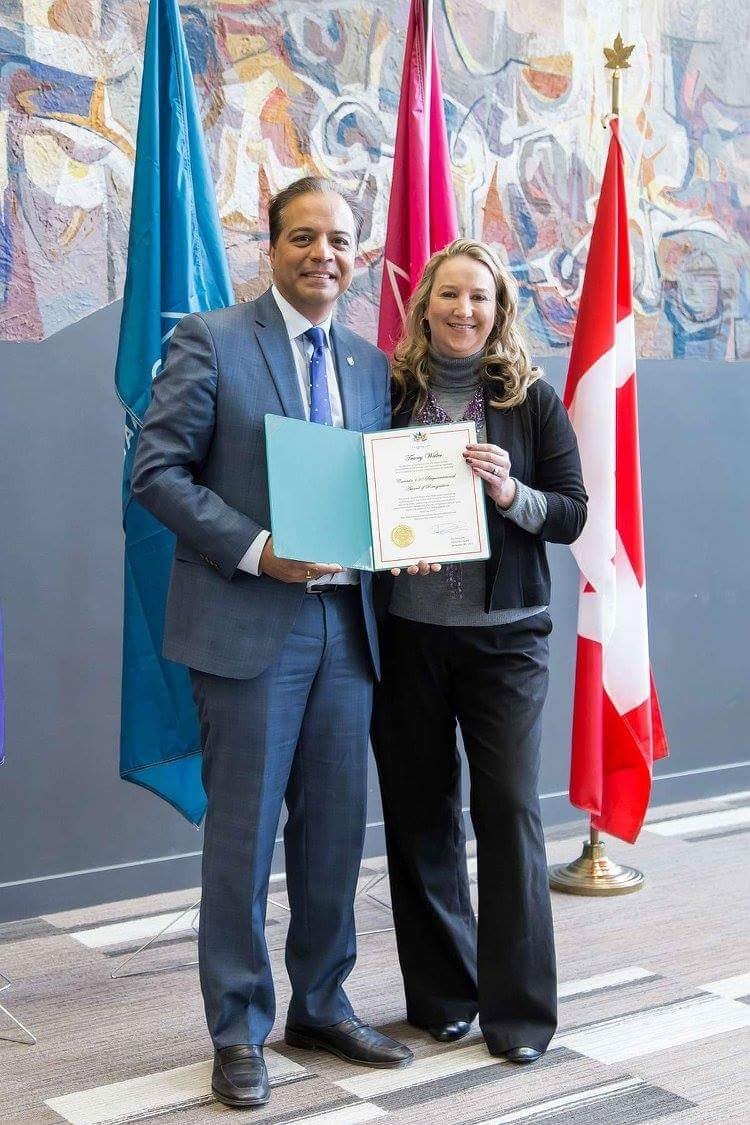 Tracey receiving an award with flags in background
